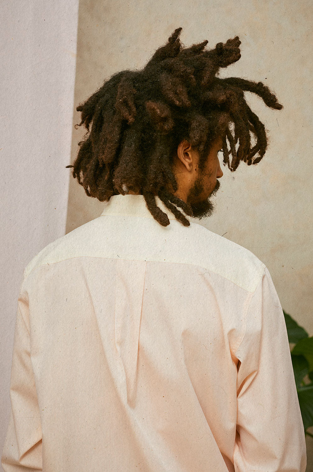 Close up back view of a man wearing Saywood's Eddy Mens Patchwork Shirt in orange and yellow. Showing the contrast back yoke and box pleat.