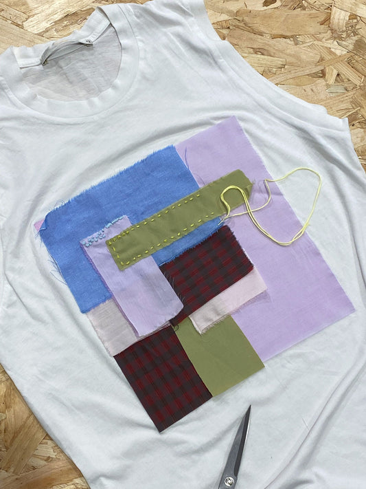 Patchworked tshirt, with different coloured pieces of fabric layered up and stitched together with embroidery. The most sustainable wardrobe is the one you already own - rewear and mend.