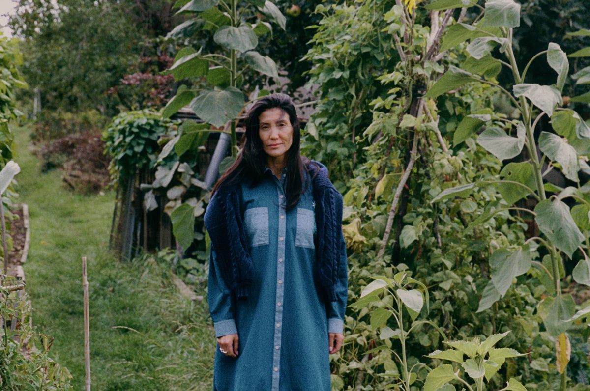 Etta Oversized Shirtdress in blue  Japanese denim with contrasting pale blue pockets and cuffs, worn by a model among tall garden plants.