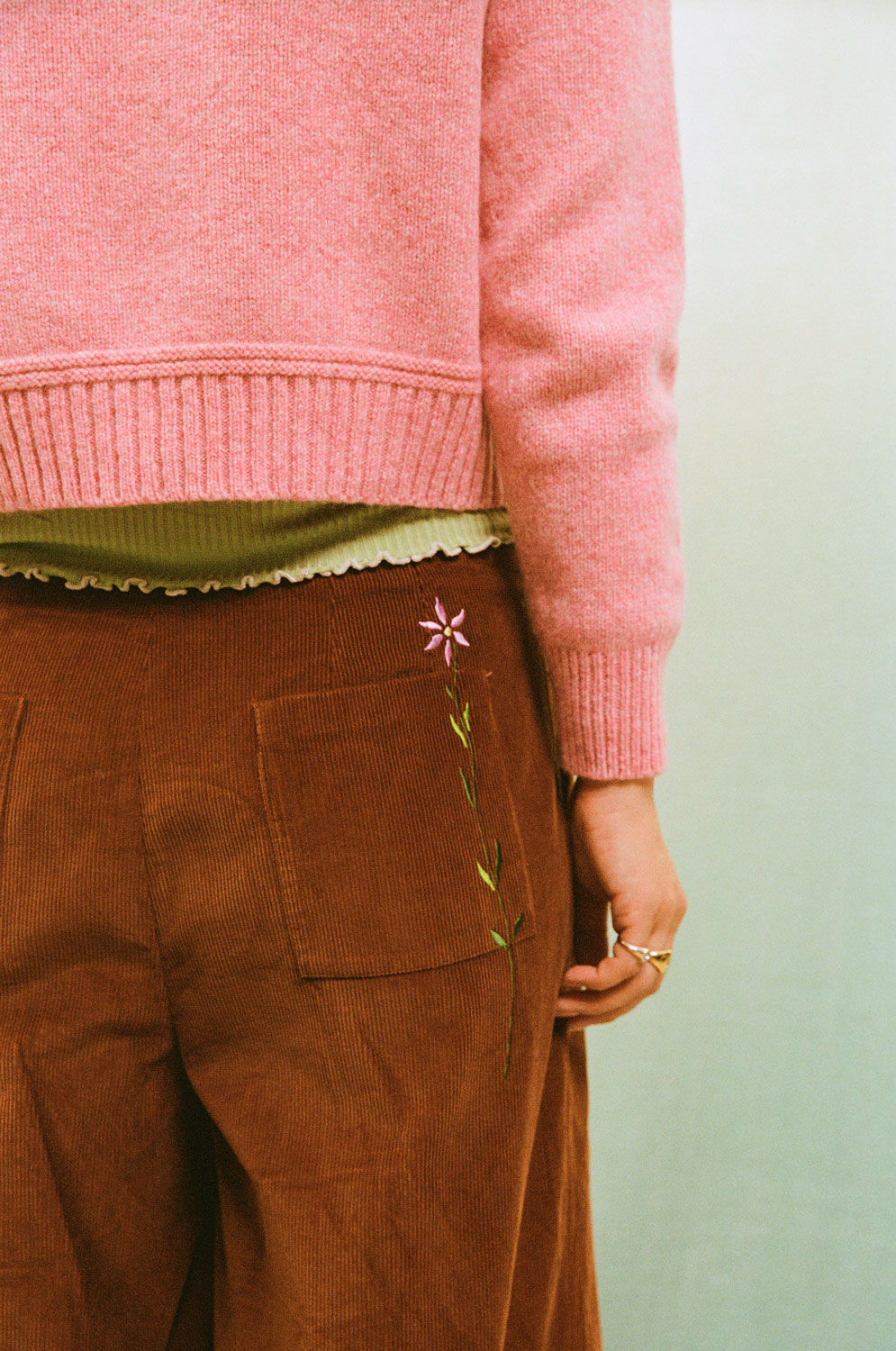 Close up back view of Amelia caramel corduroy trousers, showing the embroidered back pocket with pink Rosalind Sweater