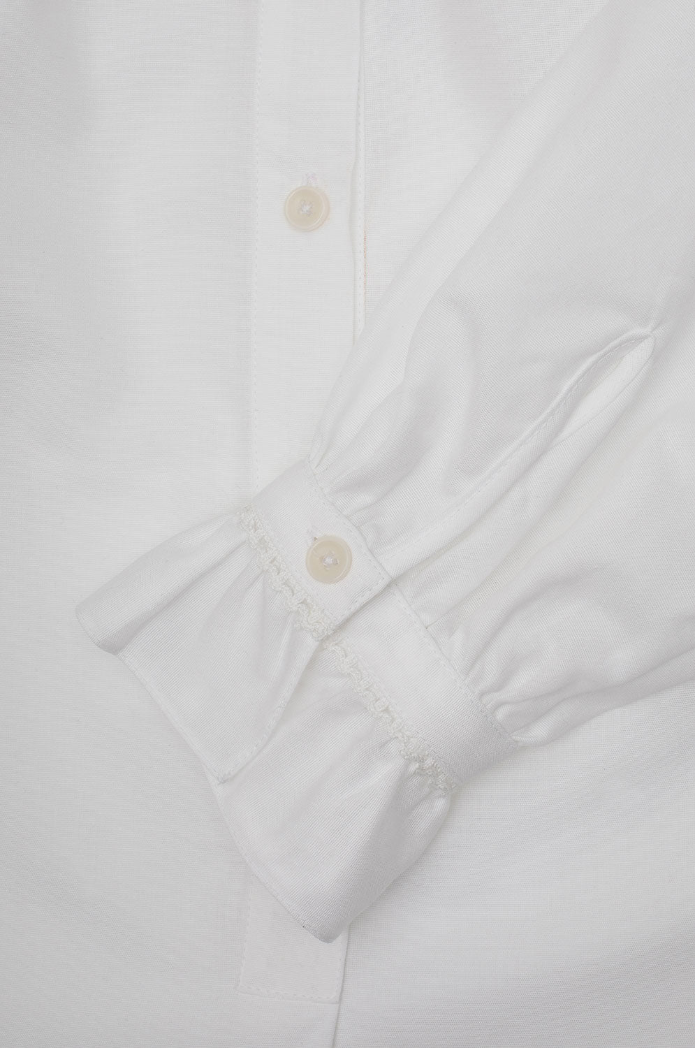 Womens White Blouse Recycled cotton. A-line silhouette with a gathered neck and frill cuffs. Marie Gather Neck Blouse by Saywood in white recycled cotton. Close up of the gathered cuffs with lace trim.