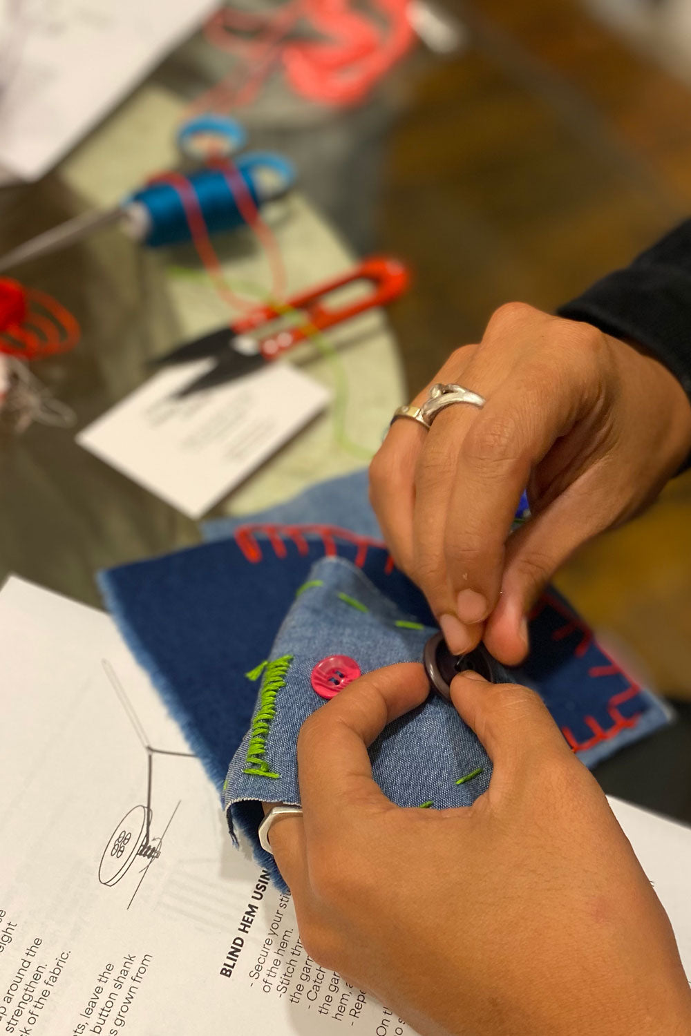 Close-up of hand stitching decorative patch onto fabric at workshop