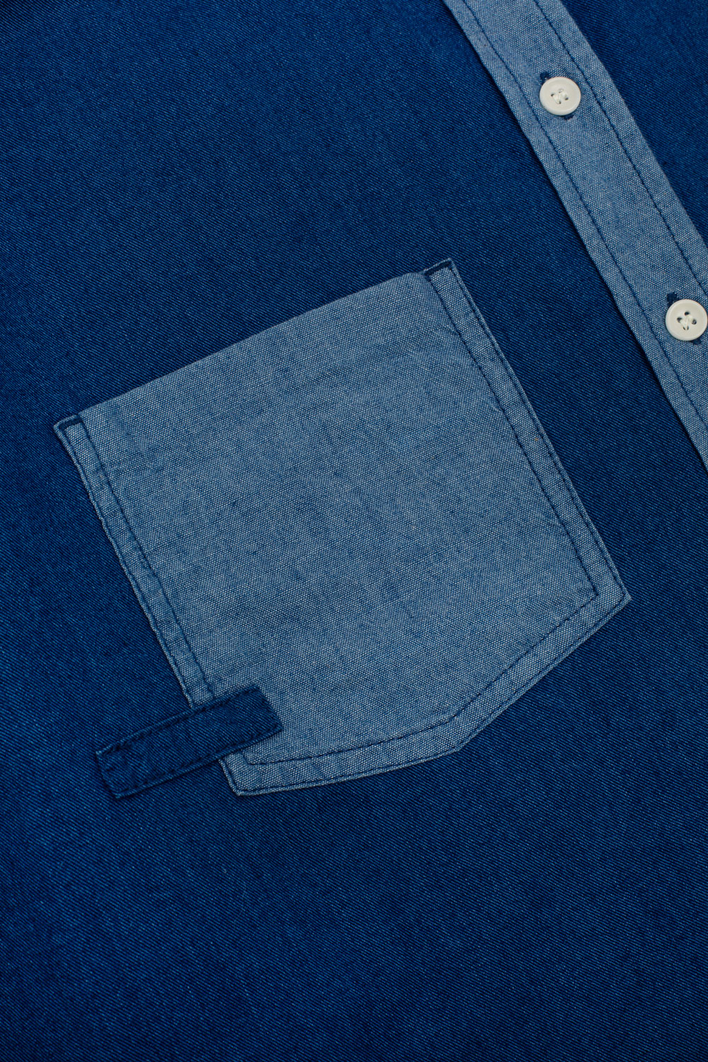 Close-up of a blue denim shirt with a pocket and buttons.