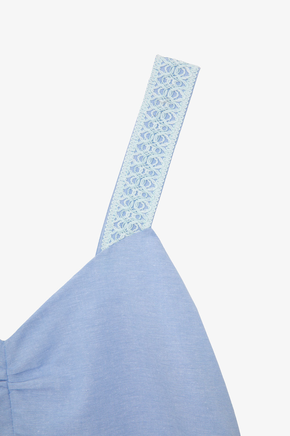 Close up detail of the lace-trimmed straps and gathered bust of the pale blue recycled cotton Maya Cami Dress, by Saywood. Made in London.