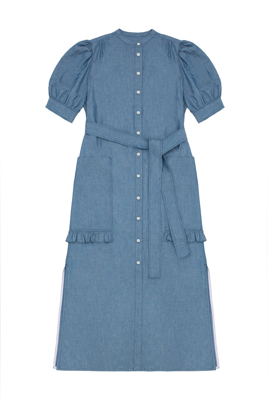 Womens denim puff sleeve dress in light wash Japanese denim, long line with side splits at the hem. Dress has patch pockets at the hip with ruffles at the bottom of the pockets, with a tied matching belt around the waist. Dress is on a white background.