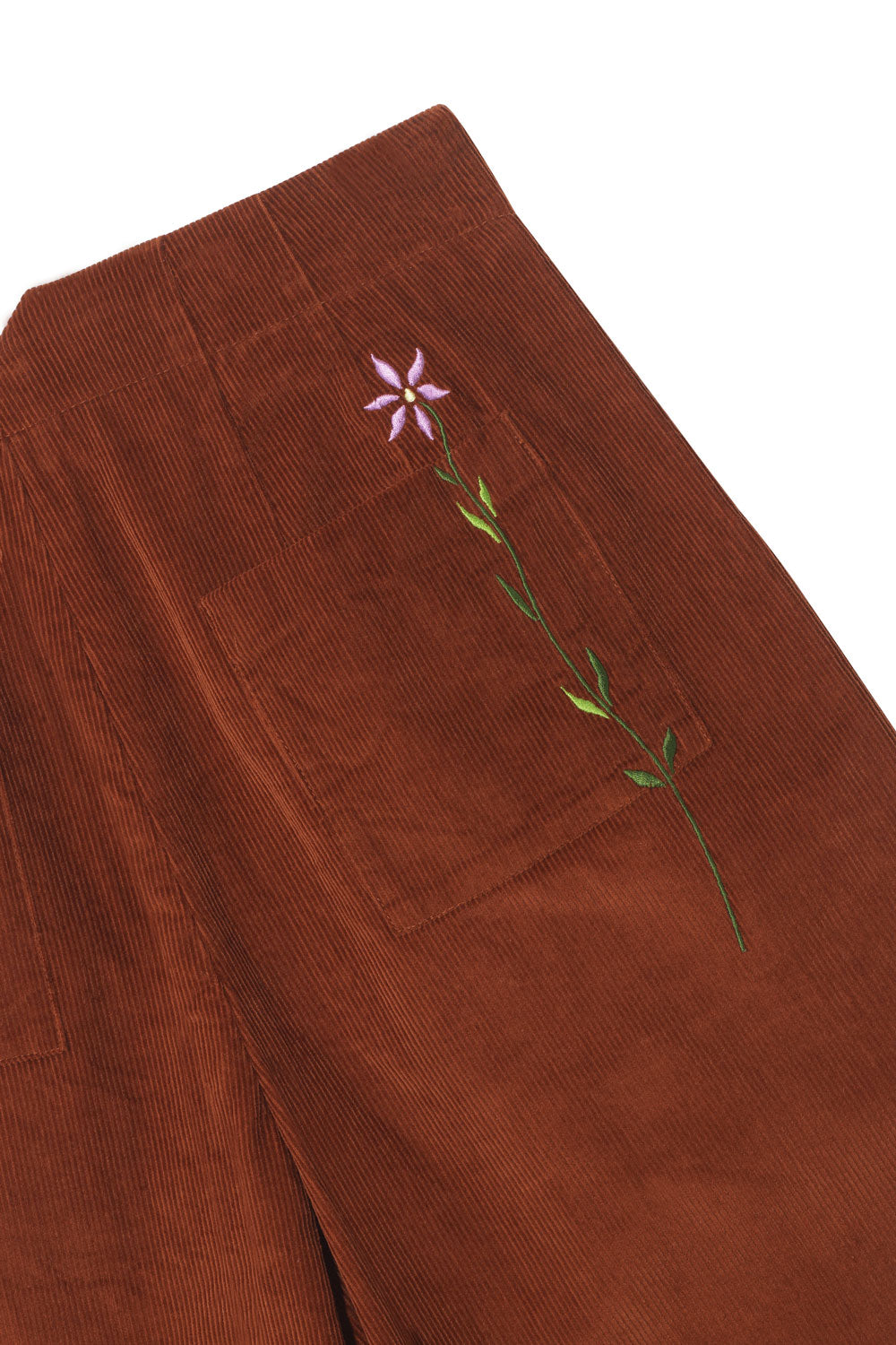 Women's Wide Leg Trouser in tan corduroy. Detail shot of back pocket with Saywood's signature flower embroidery on. Saywood's Amelia Full Length Wide Leg Trouser in caramel corduroy in 100% organic cotton, flat shot on a white background.