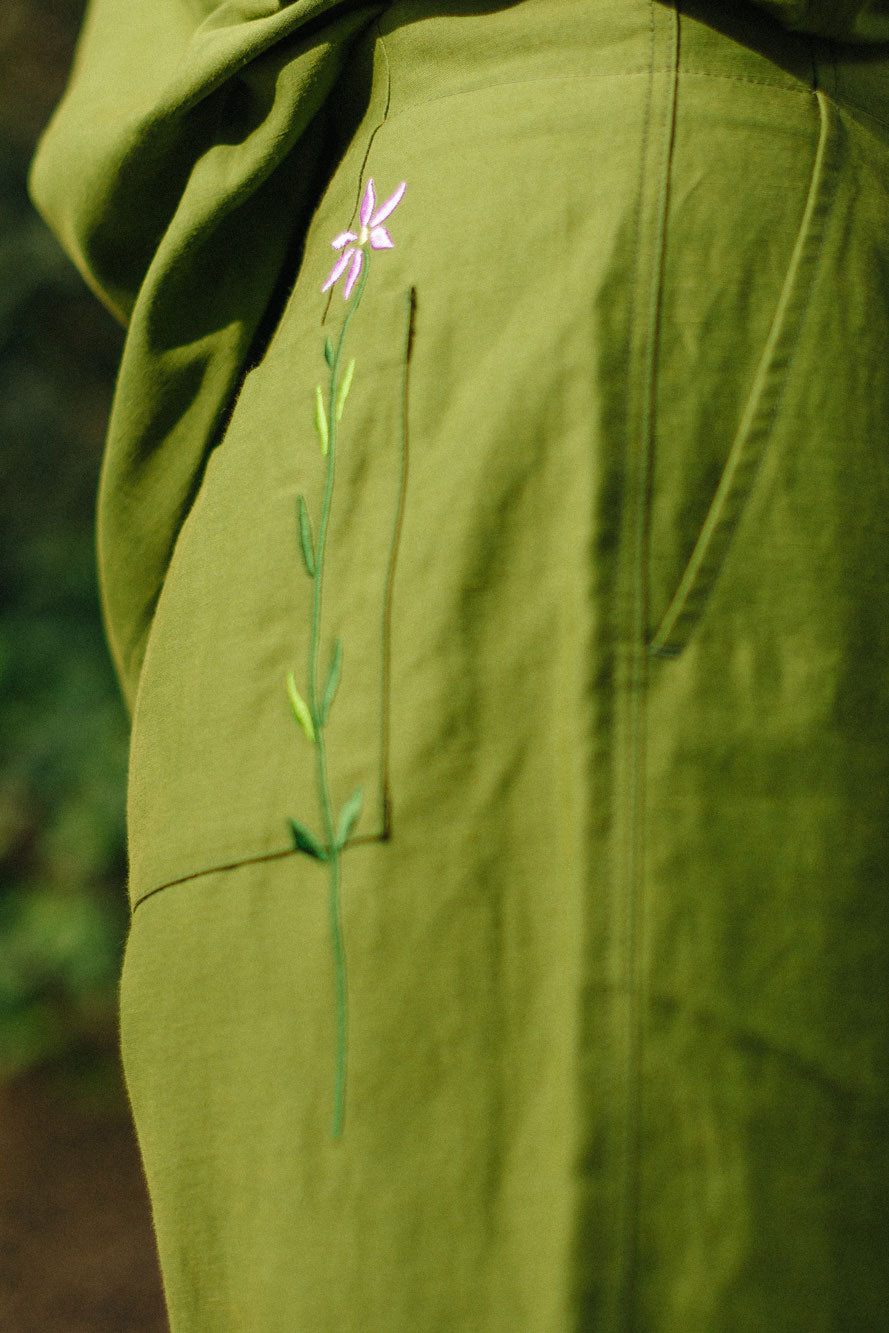 Close up of the side of the Bessie Shorts in olive green. The Saywood signature embroidered flower can be seen across the back patch pocket.