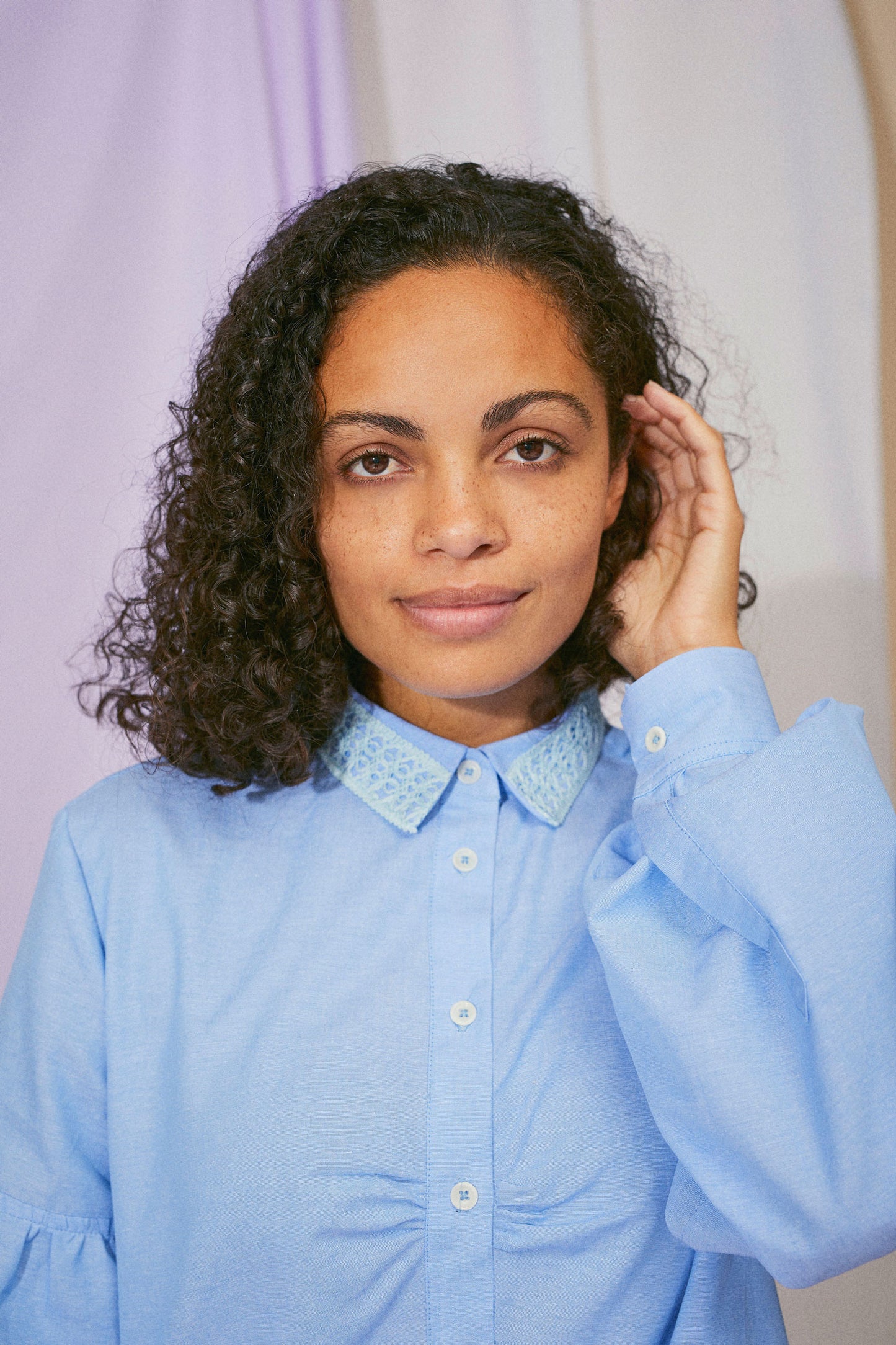 Womens pale blue shirt in recycled cotton, with lace collar trims, volume sleeves, and soft gathers at the bust, close up