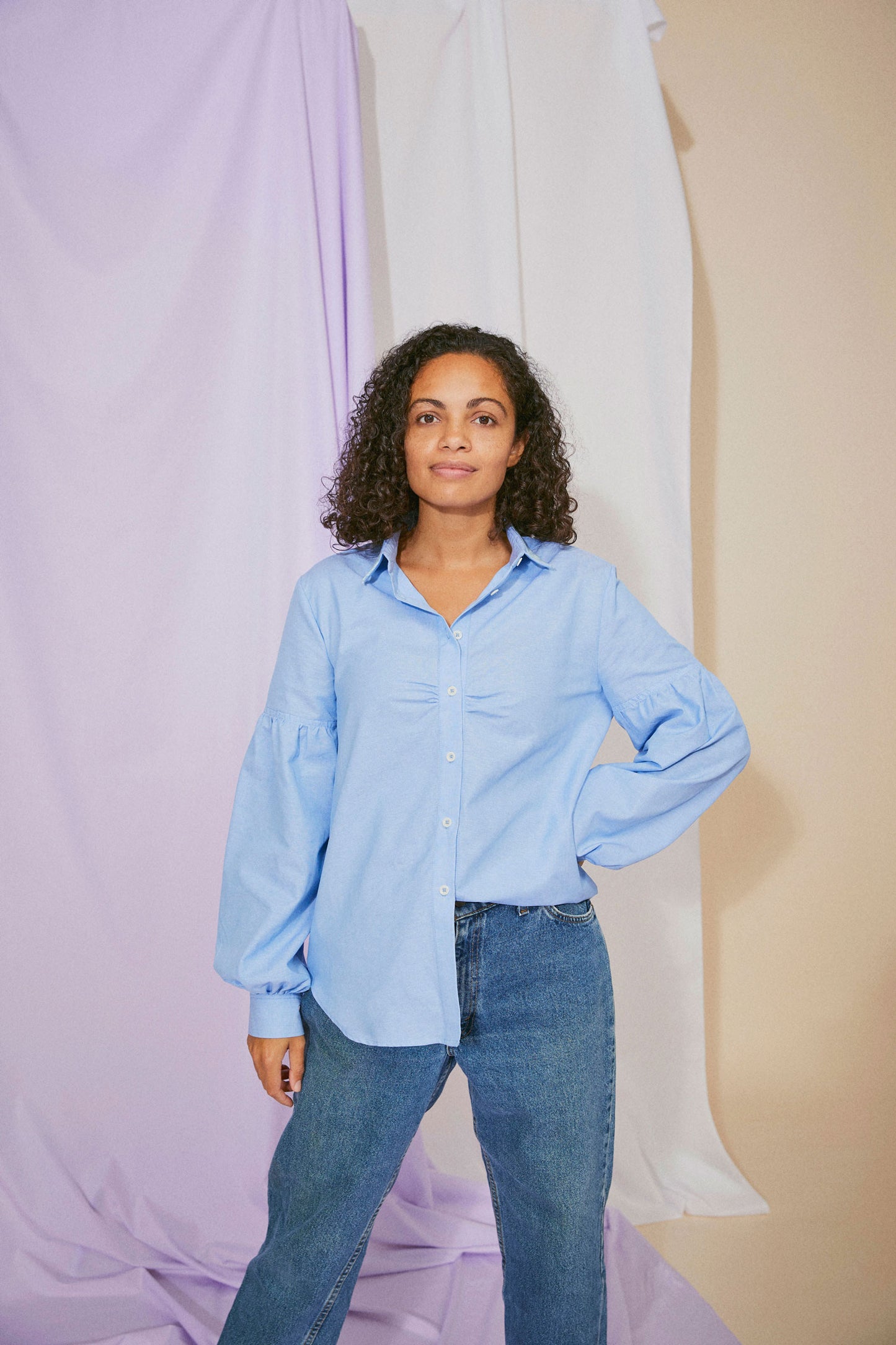 Womens pale blue shirt in recycled cotton, with lace collar trims, volume sleeves, and soft gathers at the bust, worn with jeans, half tucked