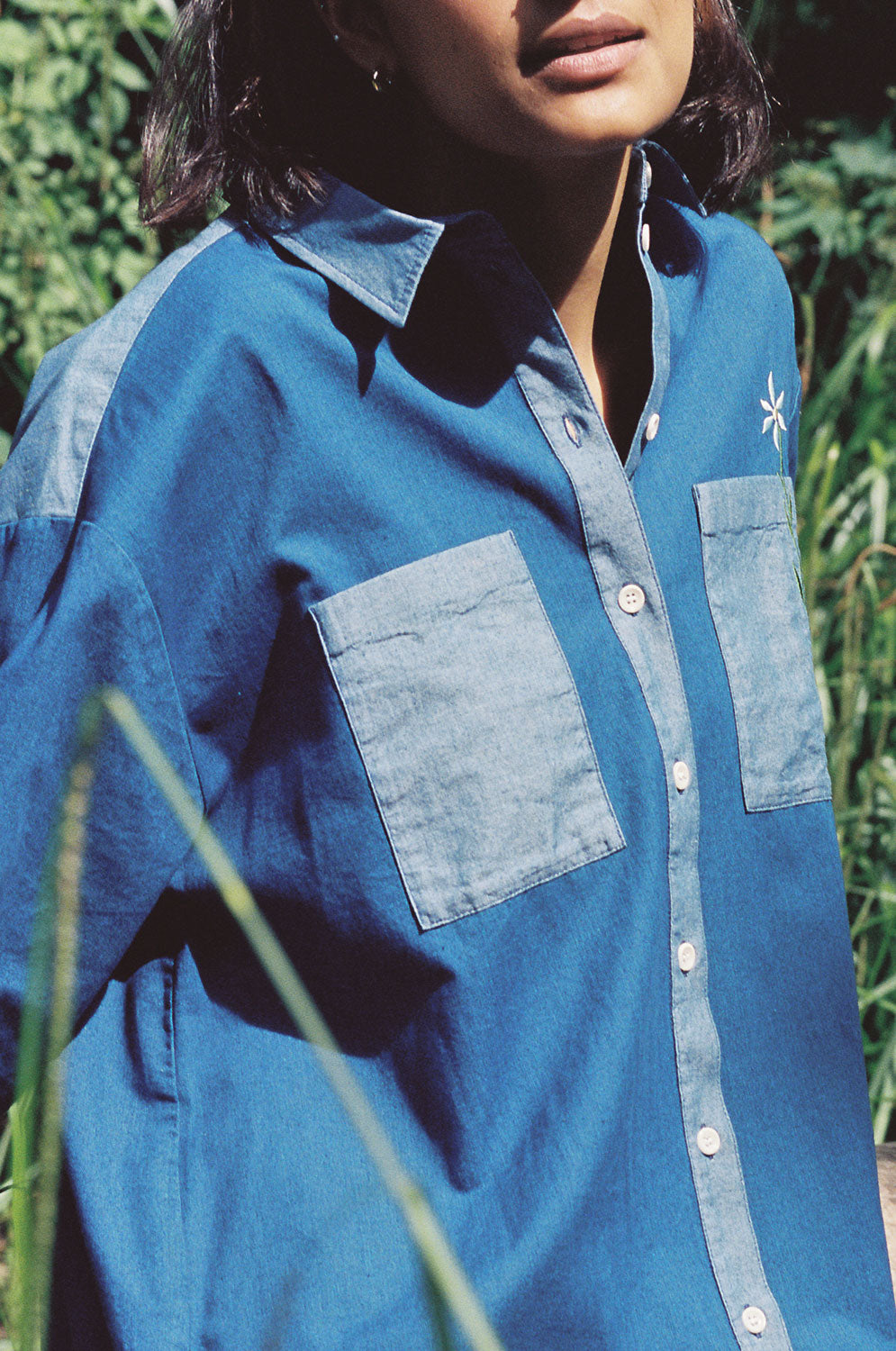 A woman wearing Saywood's blue Japanese denim Etta Oversized Shirtdress. The fabric texture and contrast denim wash details can be seen.