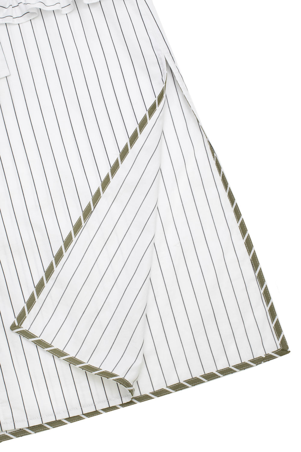 Close up of the Rosa Puff Sleeve Shirtdress white pinstripe cotton hem splits. On split is folded back and the khaki and white stripe internal hem bind detail can be seen. Flat shot of dress on white background.