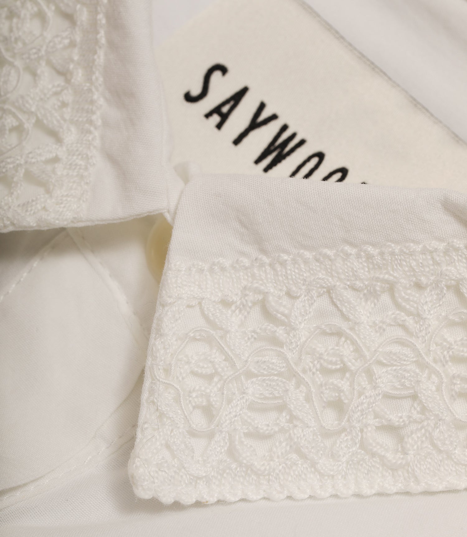 White shirt collar with textured lace trim with 'SAYWOOD' label on the neck