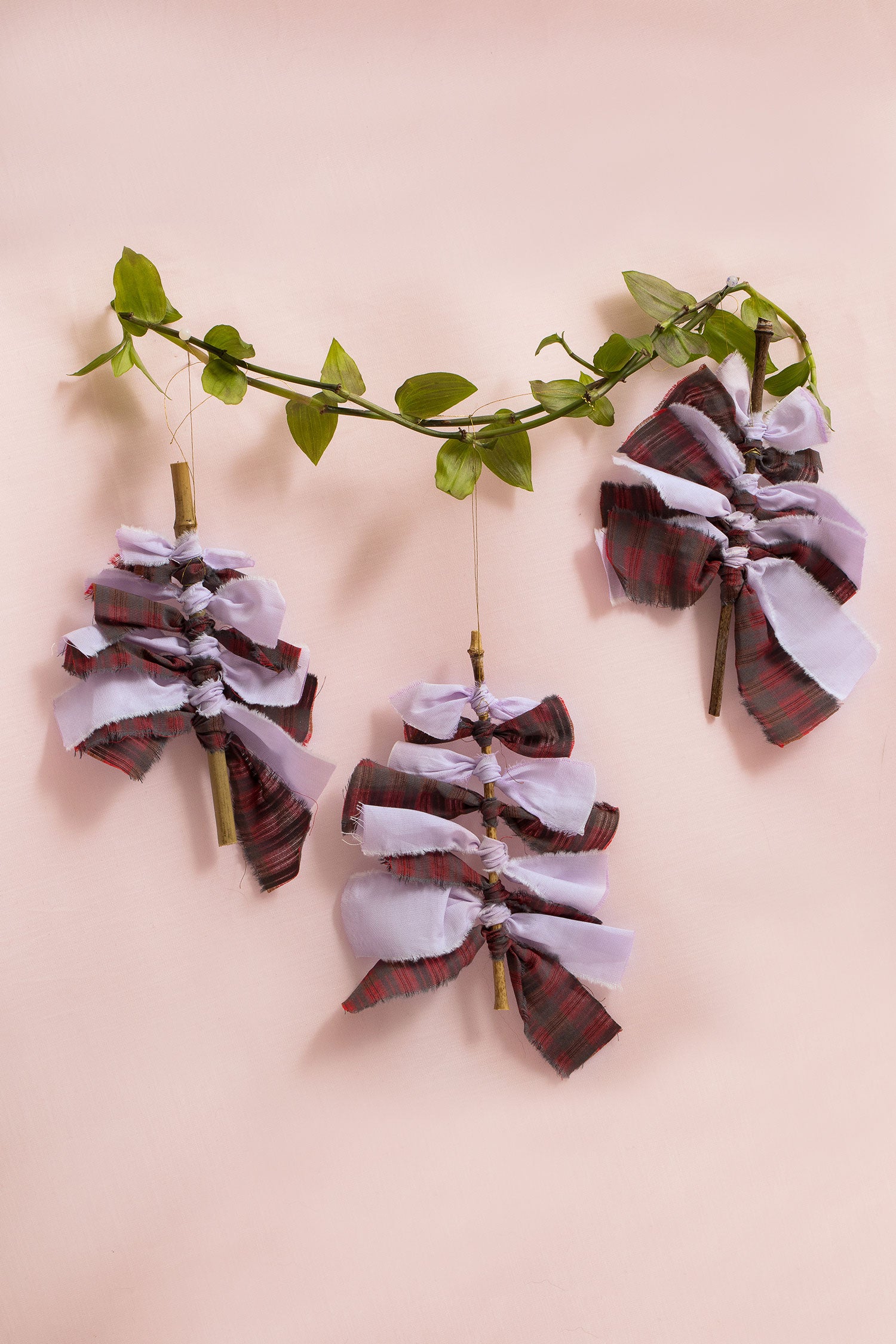 Sustainable Christmas Decorations from Saywood. Christmas tree with red check and lilac fabric tied round bamboo stick with gold thread to hang on the tree. Eco-friendly Christmas decoration